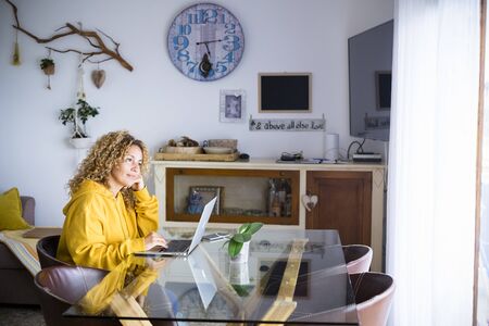 Beautiful young adult woman at home with personal laptop computer work and use modern internet technology - concept of smart work and alternative office for freelance peopleの写真素材