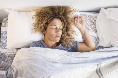 Beautiful caucasian adult woman sleep and relax at home in the bed - concept of early morning activity before wake up and go work - concept of quarantine lockdownの写真素材