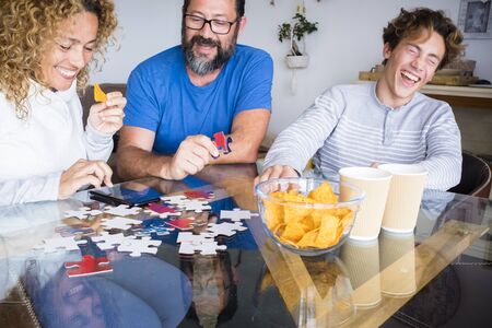 Caucasian family play together on the table at home and have fun laughing a lot - indoor leisure activity and playful time during coronavirus quarantineの写真素材