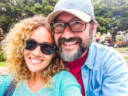Adult caucasian couple portrait with park and nature in background - city outdoor leisure activity for beautiful woman and man together in leisure activityの写真素材
