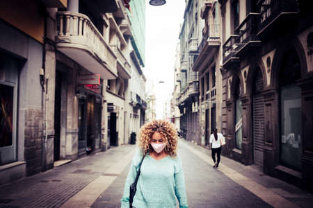 Sad woman stand in the. middle of the road in the city wearing protection coronavirus mask - concept of lockdown and economy recession phase - worldwide buiness covid-19 crisisの写真素材