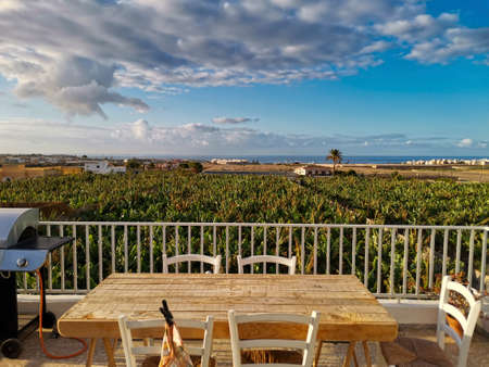 Beautiful view of wooden table and barbecue kitchen grill ready to host people to have un together - nature and home concept - blue sky and ocean in backgroundの写真素材