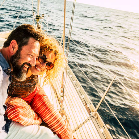 Happy and cheerful caucasian couple enjoy the sail boat trip together - sunny summer holiday vacation day for beautiful adult people enjoying yacht and ocean outdoor travelの写真素材