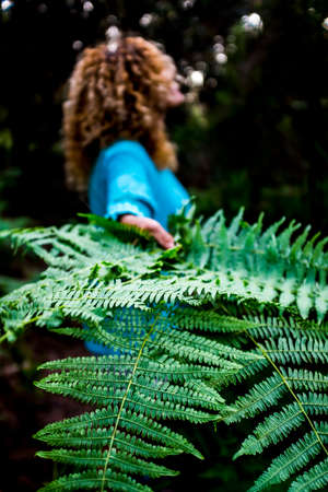 Concept of environment and save the planet earth with close up of tropical green leaf and woman in background - nature and outdoor forest care for people loves the outdoorsの写真素材