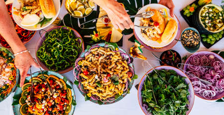 Vertical view of people firends hands taking food from catering table during party celebration - catering and restaurant concept with mixed chef food on a table -coloured background and togetherの写真素材