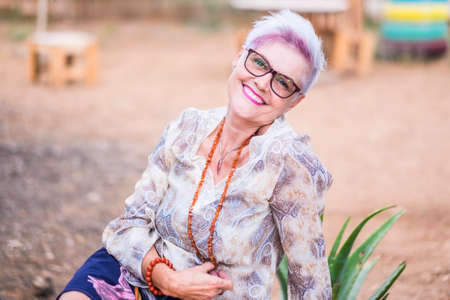 Beautiful alternative senior mature woman with punk hipster hippy style white and violet hair smile at the camera posing for a portrait - happiness and retired lifestyle conceptの写真素材