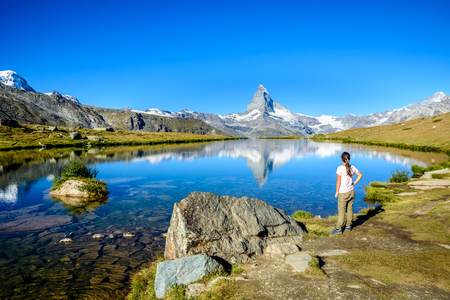 Hiker at Stellisee - beautiful lake with reflection of Matterhorn - Zermatt, Switzerlandの写真素材