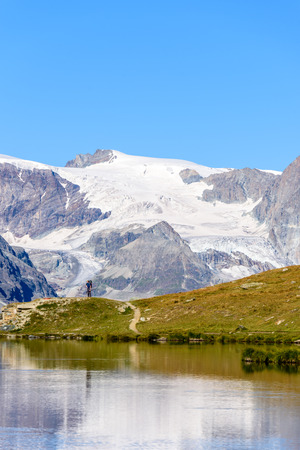 Hiker at Stellisee - beautiful lake with reflection of Matterhorn - Zermatt, Switzerlandの写真素材