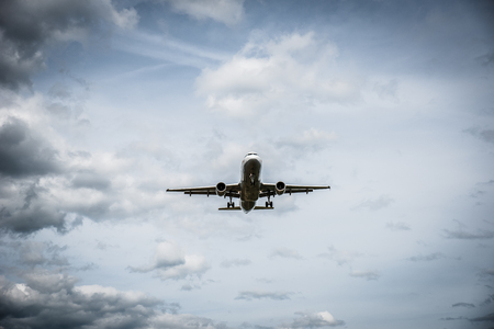 Airplane flying with clouds in backgroundの写真素材
