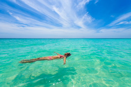 Attractive young woman relaxing in turquoise waters of Caribbean Sea in front of paradise beach in Tulum, close to Cancun, Riviera Maya, Mexicoの写真素材
