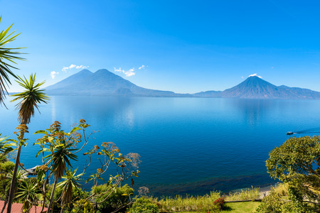 View from Lake Atitlan in the early morning, blue skys and clear water, beautiful magic lake with volcanos and indigenous people in the highland of Guatemalaの写真素材