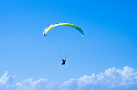 Paraglider is flying in the blue sky against the background of clouds. Paragliding in the sky on a sunny day. Extrem Sport and recreation.の写真素材