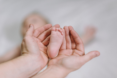 Baby feet in the hands of mother - cute newborn in the hands of mum - happy family momentsの写真素材