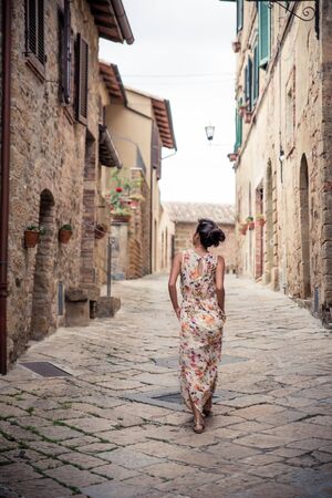 Young asian girl walking in Monticchiello town on summer day. Amazing promenade with traditional old stone houses - Tuscany, Italy, Europeの写真素材