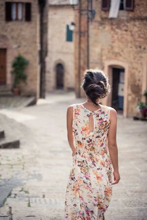 Young asian girl walking in Monticchiello town on summer day. Amazing promenade with traditional old stone houses - Tuscany, Italy, Europeの素材 [FY310128120086]