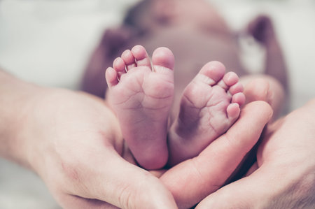 Feet of a newborn baby in the hands of parents. Happy family moment and concept.