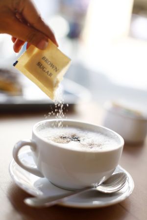 Brown Sugar being Poured into a Cup of Cappuccinoの写真素材