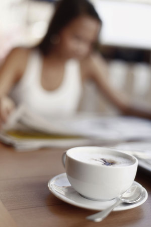 Cup of Cappuccino Coffee with Asian Female in Backgroundの写真素材