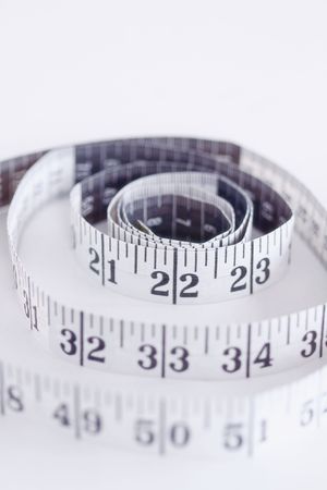 Imperial Tape Measure Rolled out on a White Surfaceの写真素材