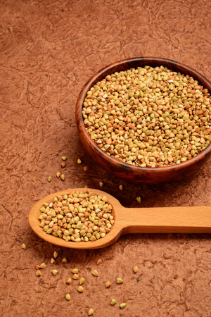 dry buckwheat grains in wooden spoon and bowlの写真素材
