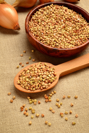 dry buckwheat grains in wooden spoon and bowlの写真素材