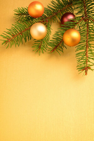 Fir branch with Christmas balls over golden backgroundの写真素材