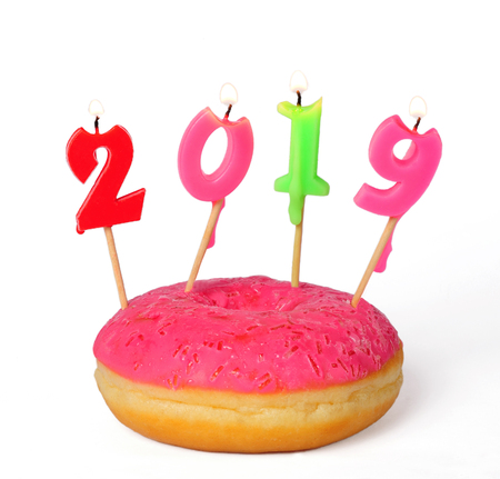 pink donut with burning candles 2019 isolated over white backgroundの写真素材
