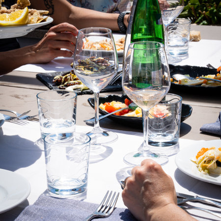 Wine glasses and food on the table in a restaurant. People enjoy the meal in a typically Italian day. Selective focus.の写真素材