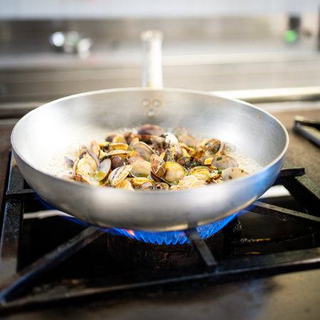Cooking clams in a pan on a gas stove in a restaurantの写真素材
