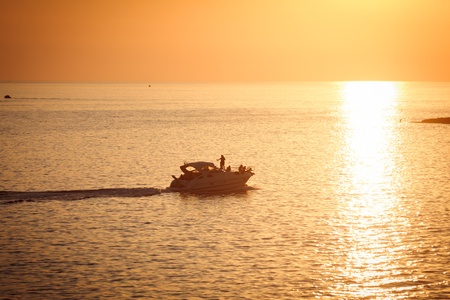 turist ship in backlight, at sunset, in the water of south italyの写真素材