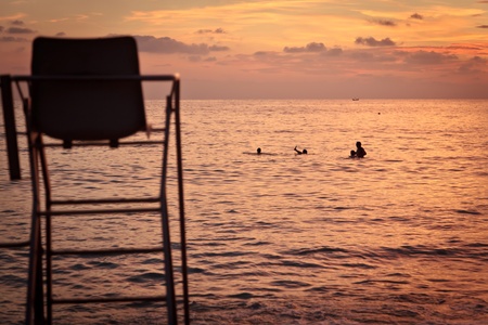 people swimming at the sunset, in front of the lifeguard chairの写真素材