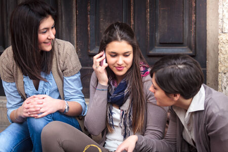 three happy girls messaging with mobile phone after shoppingの写真素材