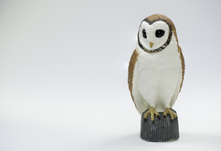 Owl Figurine sitting on wooden stump with black eyesの写真素材