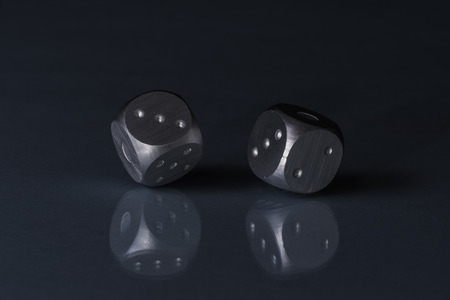 Two Rolling Silver Casino Dice on Black Background with blue bottomの写真素材