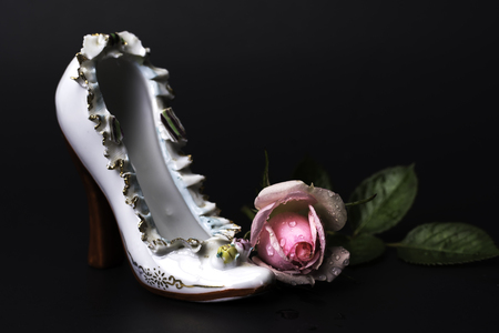 Vintage porcelain high heel white Victorian shoe with wet pink rose on back background.の写真素材