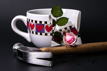 Broken Heart Cup with got shattered with hammer and pink rose on Black Backgroundの写真素材