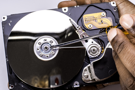 Male technician hand holding and working on dusty computer hard drive with scewdriverの写真素材