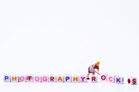 Miniature figurine woman fixing adjusting a Group Of Letters forming Words Spellingの写真素材
