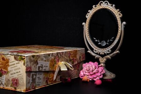Vintage Oval Desk Mirror with white frame, Potpourri pieces and a keepsake box on black backgroundの写真素材
