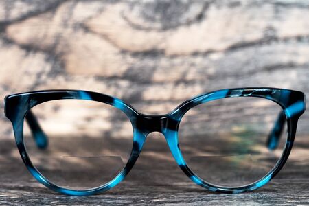 Eyeglasses Glasses with Bifocals and Black Blue Frame smudged  Fashion Vintage Style on Wood Desk Background, Rustic Still Life Style.の写真素材