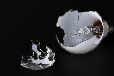 Broken lightbulb isolated on black backgroundの写真素材