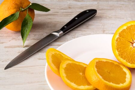 Oranges and Orange Slices with knife on white plate with leafs on white marble. Citrus Food Photography.の写真素材