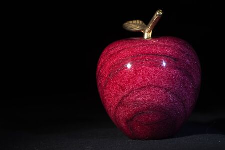 decorative marble Apple with a Golden branch and leaf on black backgroundの写真素材