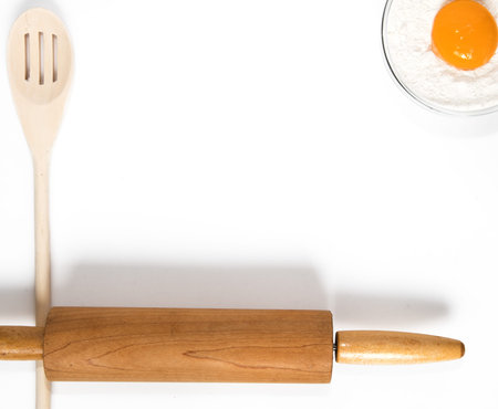 Wooden Spoons and rolling pin for baking and cooking with flower and egg yolk.  Top View on white...