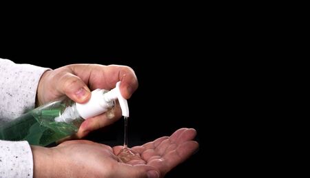 Corona Virus Protection. Hands using hand sanitizer gel pump dispenser. Health concept for killing germs, bacteria and virus. Black background with copy spaceの写真素材