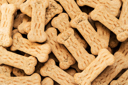 Pile of Bone shaped dog biscuits of brown color. Abstract wallpaper.