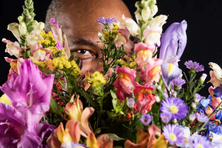 Friendly African American with colorful flower bouquet on black background.  Mothers Day or Valentines Day conceptの写真素材