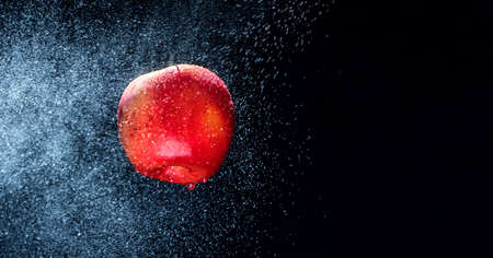 Fresh  Variegated apple  gets sprayed with water on black background. Concept of summer, health and fun. Copy Spaceの写真素材