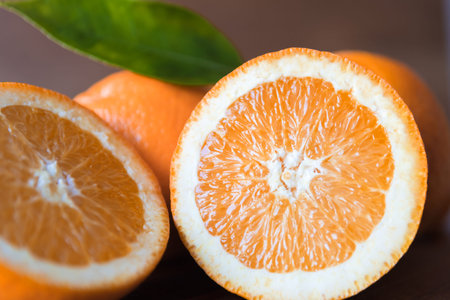 orange cut in half on rustic wooden surface and leaf