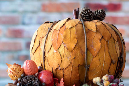 Decorative pumpkin made of yellow leafs isolated against red brick wall background. Thanksgiving conceptの写真素材